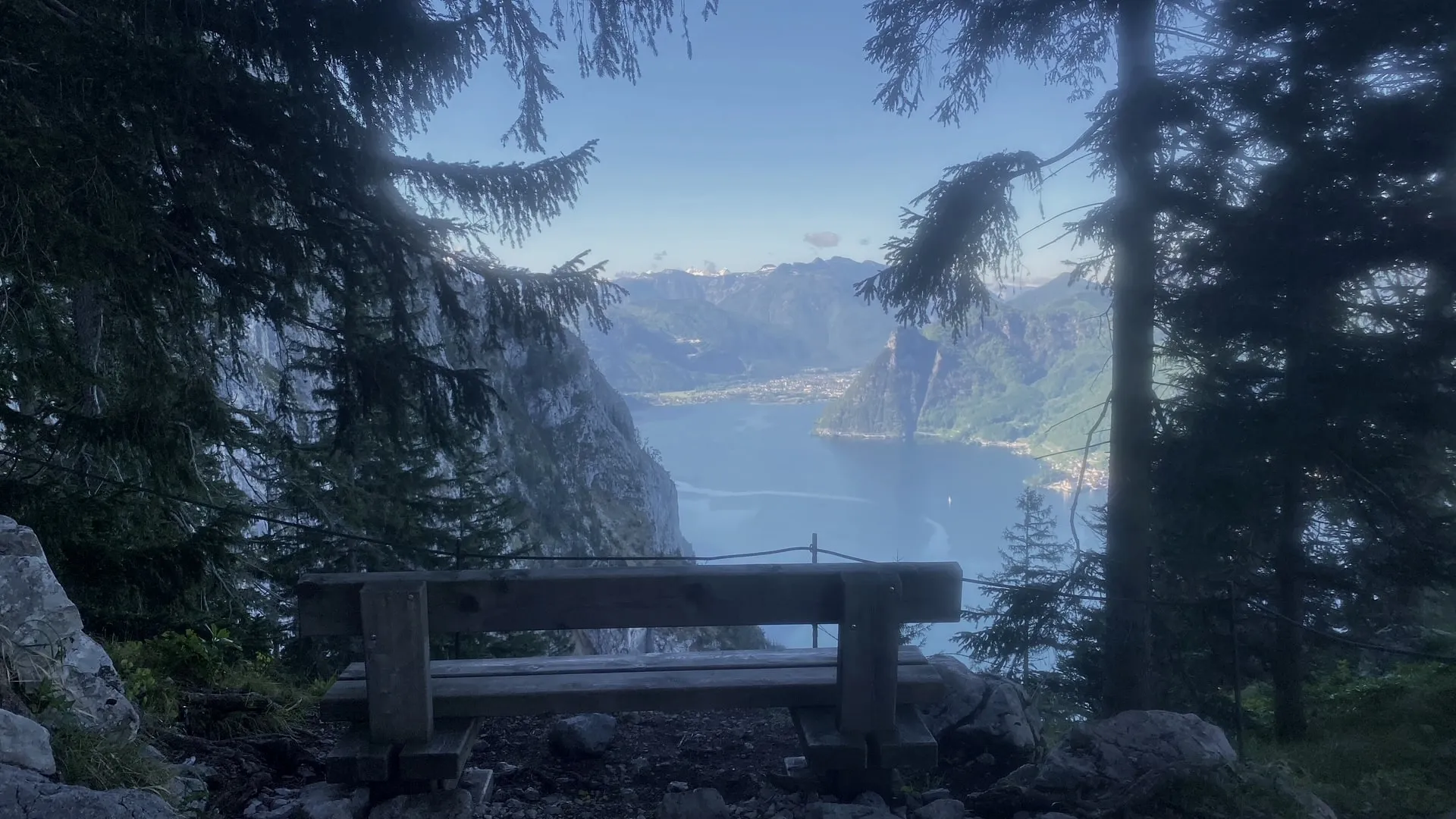 Un banco de madera a media altura, detrás la vista sobre el lago Traunsee hasta el Höllengebirge
