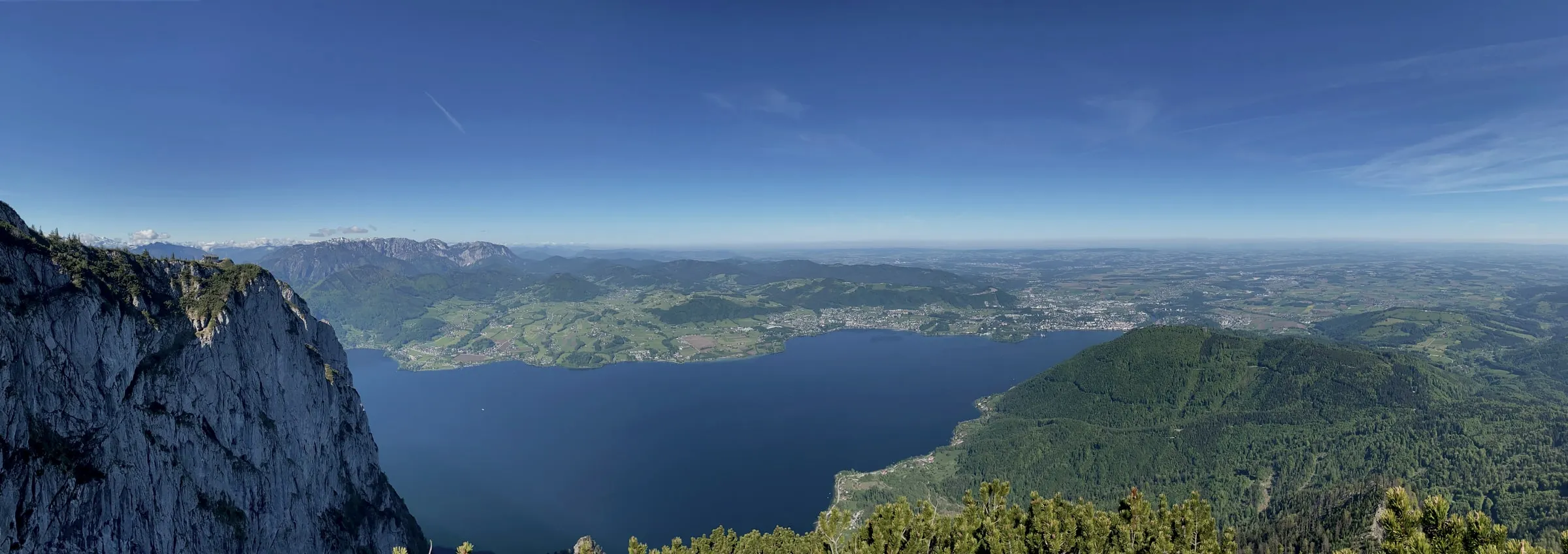 Amplio panorama desde el Traunstein sobre todo el lago Traunsee, la pared caliza vertical a la izquierda, Gmunden y el antepaís alpino a la derecha